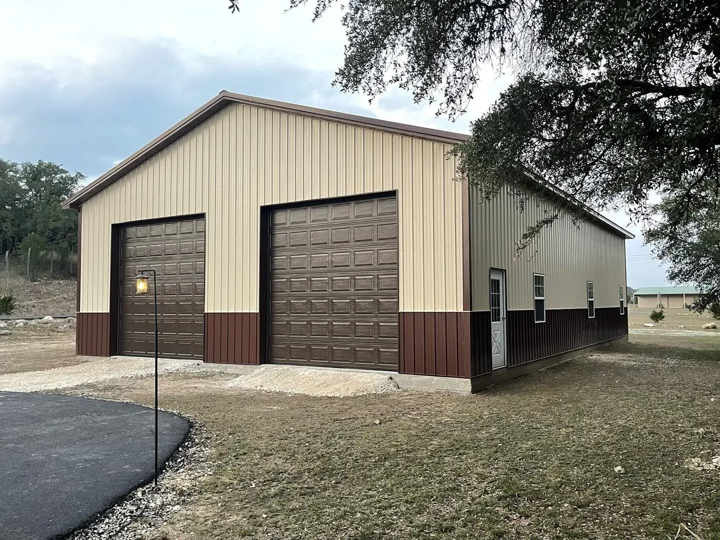 A tan and brown two-bay steel garage with a paved driveway in Texas